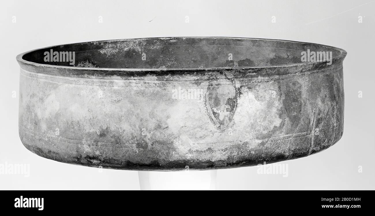 Bronze basin with upright wall and narrow, protruding, triangularly thickened edge. Faintly arched bottom, which is rounded, angularly separated from the wall, and which is strongly angled in the middle. On the wall 2 double, all-round grooves. On the curved part of the bottom 2 double all-round grooves, double grooves running all around on the dented part 2. On the inside on the wall 2 double grooves and on the middle of the bottom double grooves. The location where 2 sheet-shaped attachments were soldered can still be seen. Little, dark patina, hardly patinated in some places., Crockery Stock Photo