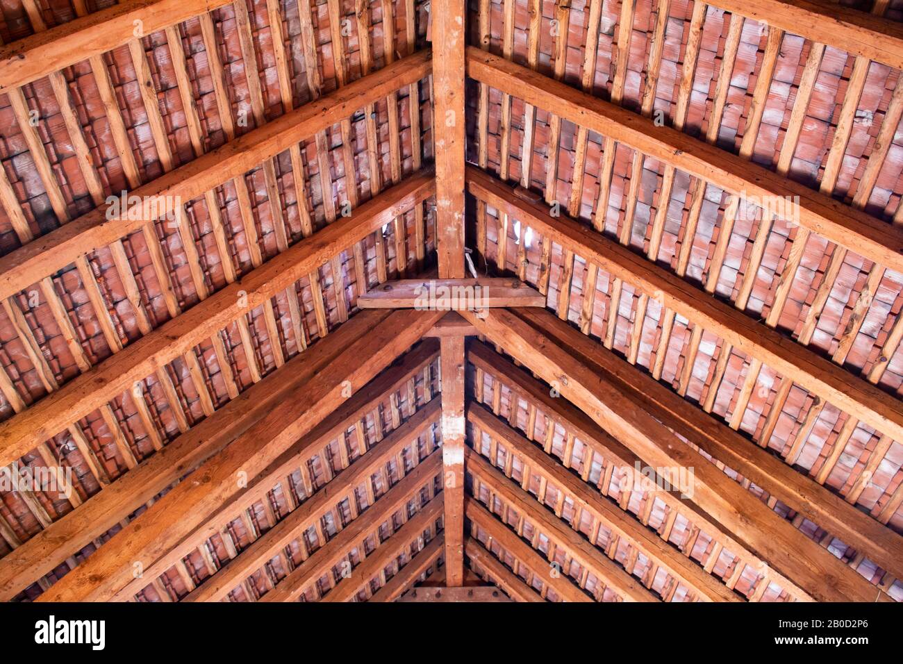 Wooden roof ridge in a old attic with view of the roof shingles Stock Photo