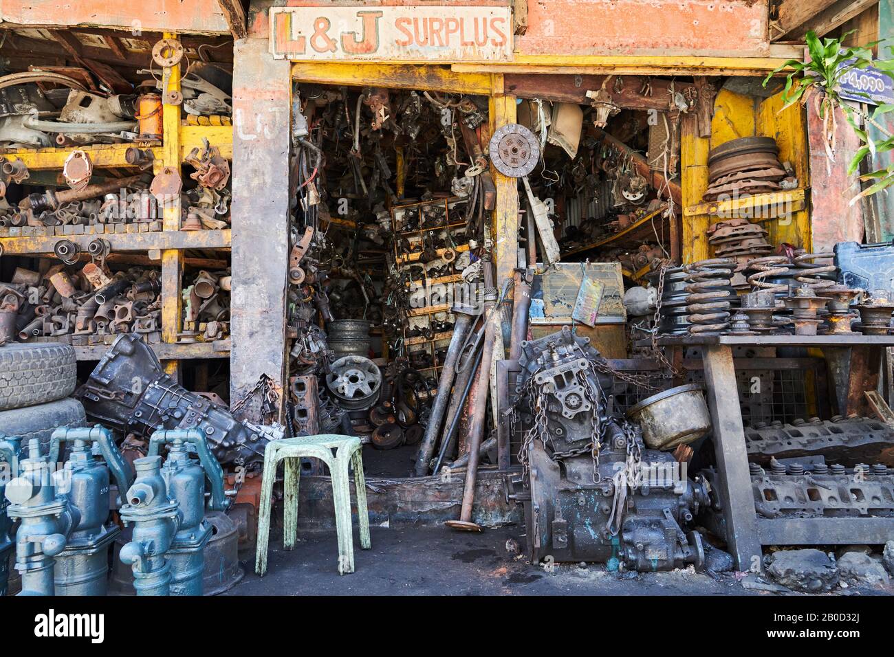 Iloilo City, Philippines: Close-up of an auto junk and repair shop with used rusty and oily engine parts, wheels, and water pumps Stock Photo