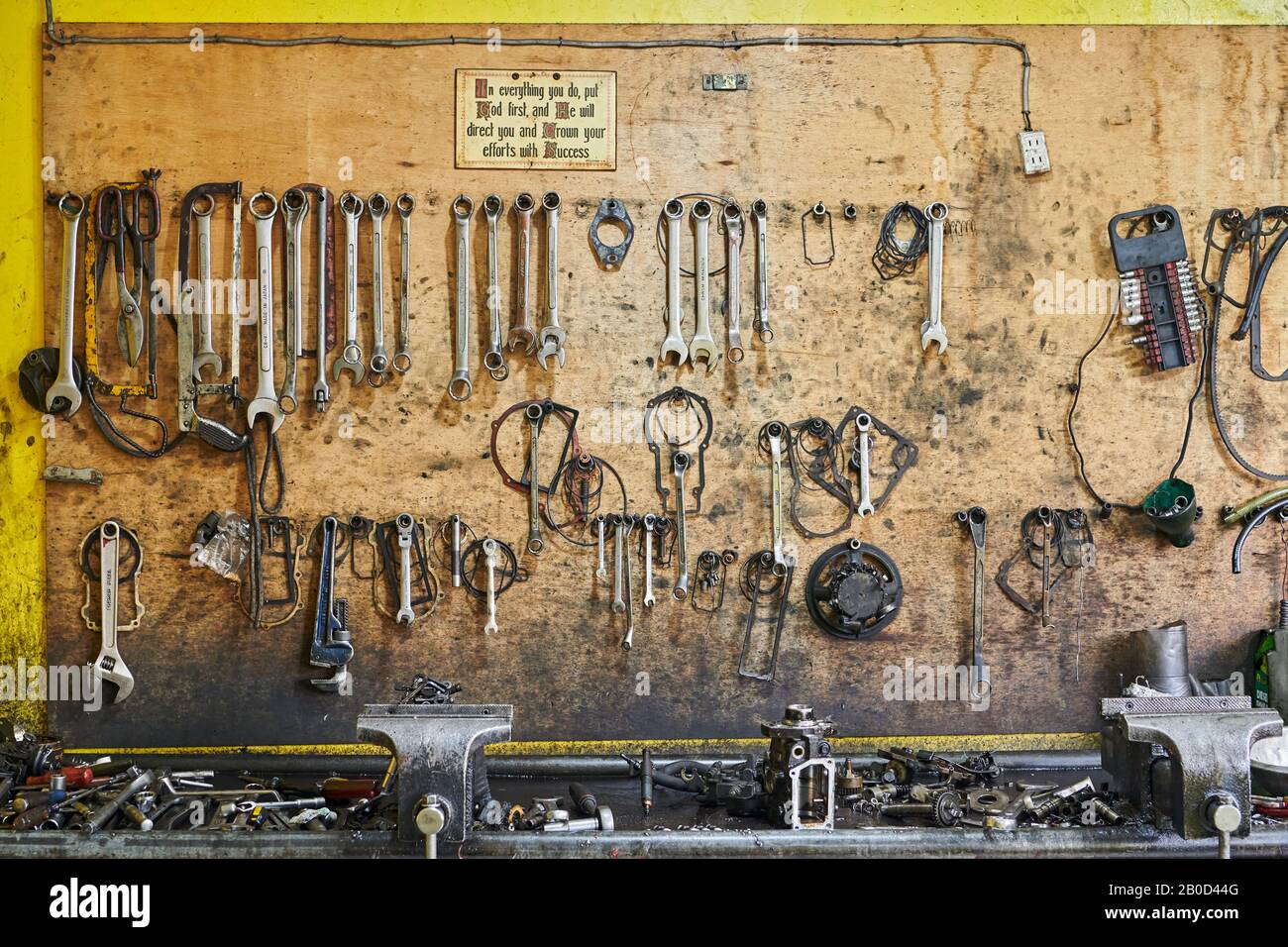 Iloilo City, Philippines: Close-up of a tool board and oily spare parts in a car repair shop, with a religious motivation sign Stock Photo