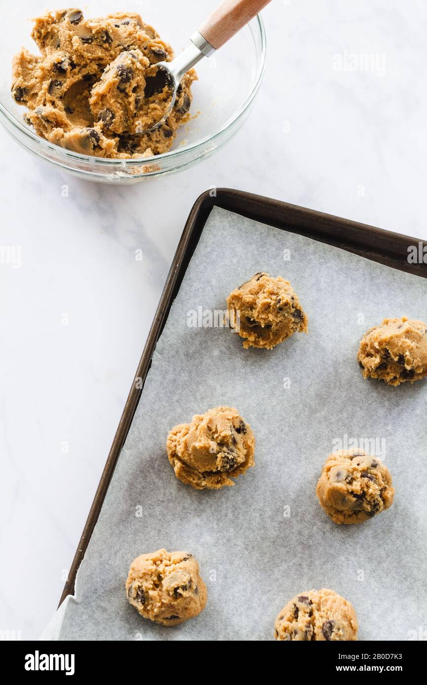 Raw chocolate chip cookie dough in a glass bowl and on a tray Stock Photo
