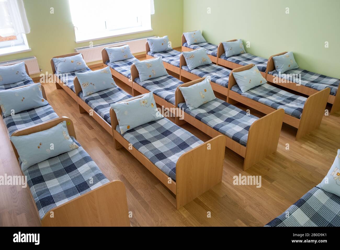 Many small beds with fresh linen in daycare preschool empty bedroom interior for comfortable