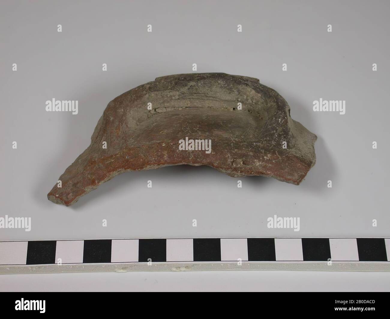 Fragment of a cooking pot including handle. The fragment contains a part of the edge and the wall. The handle is completely plastered against the wall and edge. The edge is clearly projecting but does not take the handle with it. The color is dark red. The handle contains some black discolouration which may indicate use in fire., Crockery, pottery, L 10.3 cm, W 5.4 cm, Hellenistic Period 332-63 BC, Palestine Stock Photo