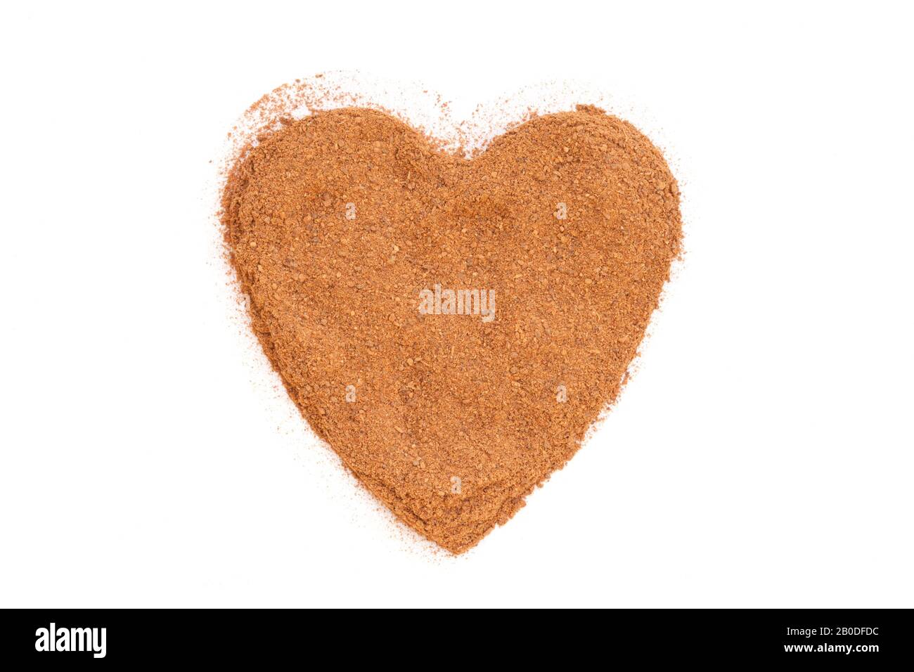 Heap of ground Cinnamon isolated in heart shape on white background.  As a spice or condiment cinnamon sold in the form of sticks or a hammer. Stock Photo