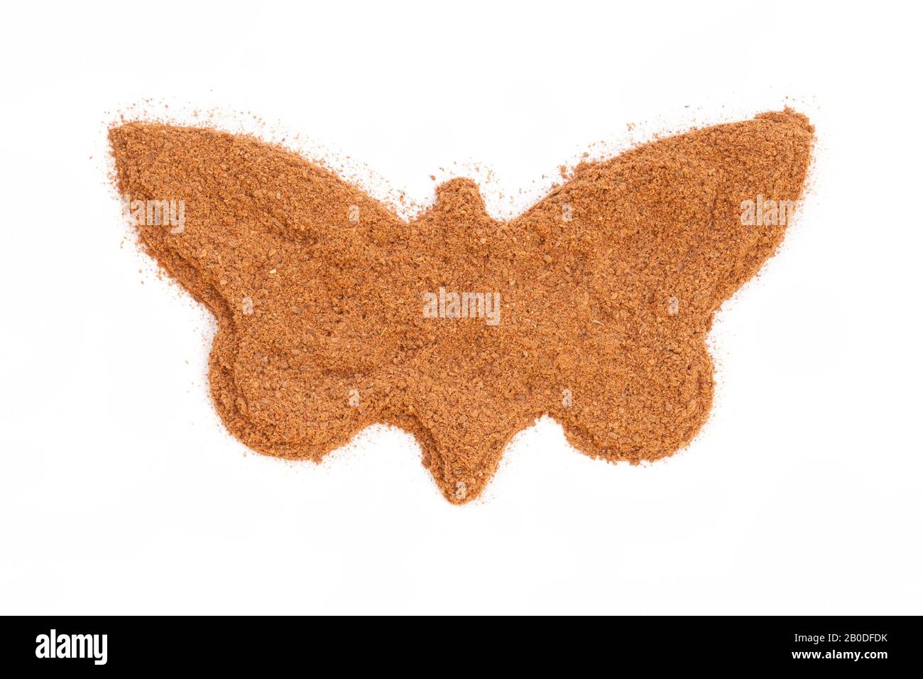 Heap of ground Cinnamon isolated in butterfly shape on white background.  As a spice or condiment cinnamon sold in the form of sticks or a hammer. Stock Photo