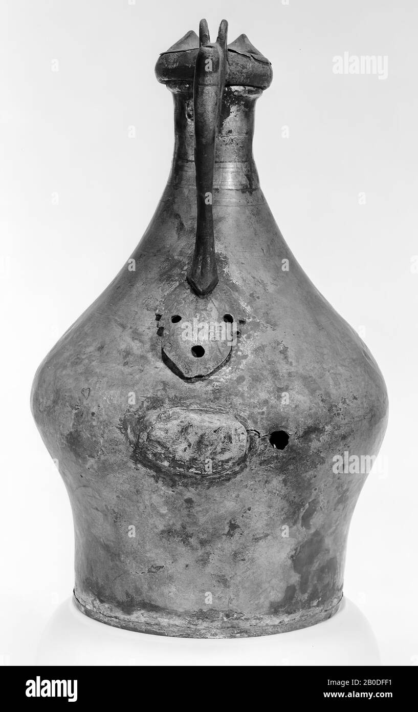 Can of bronze tin with dented bottom, soldered to the jug. Low stand ring. The wall runs quite steeply upwards to go back diagonally after the abdominal distention and gradually move into the tubular neck. Separately molded ear with pointed, leaf-shaped attache and a ring that runs around the neck and ends in a spout. On the ear a hinge for the lid that has disappeared and a thumb support. An extension piece under the hinge, which is drilled through to secure a bronze band for reinforcement. Almost without patina. Damaged and restored with a plate of bronze tin. Fine double grooves around neck Stock Photo