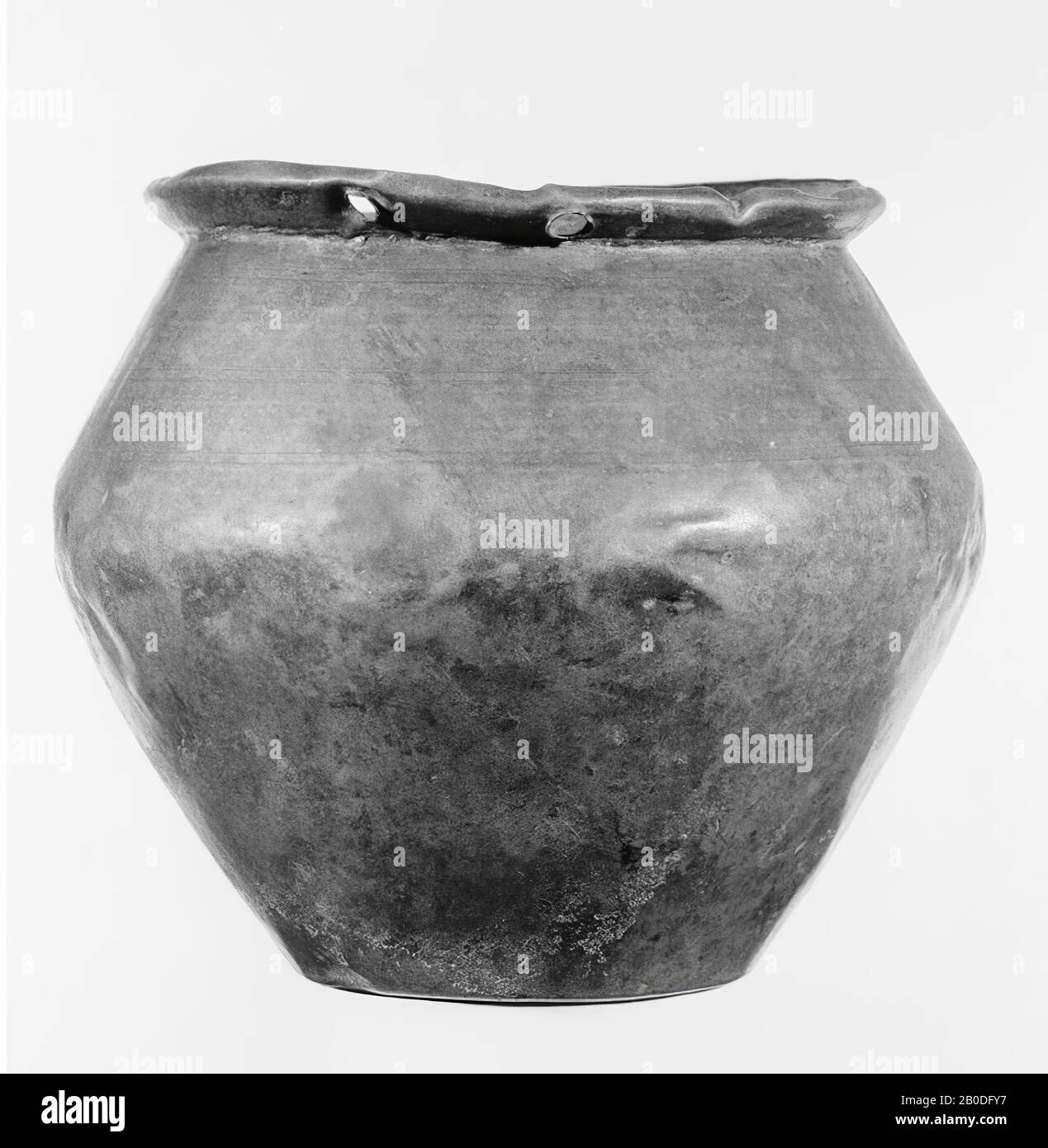 Bronze pail with slightly dented bottom and wide, rounded belly, which has its largest width above the middle. Obliquely outwardly projecting edge, the upper part of which is on the right. In the border 2 pairs of opposed holes for fastening the attachments of the handle. On the upper part of the wall 3 double circumferential grooves. On the bottom in 3 places solder tracks of feet? Hardly patinated. A stamp on the bottom: IMROMI? Or: PRIMI ?, crockery, bucket, metal, bronze, height: 13.1 cm, Roman 1-300, Netherlands, Gelderland, Nijmegen, Nijmegen, Waal Stock Photo