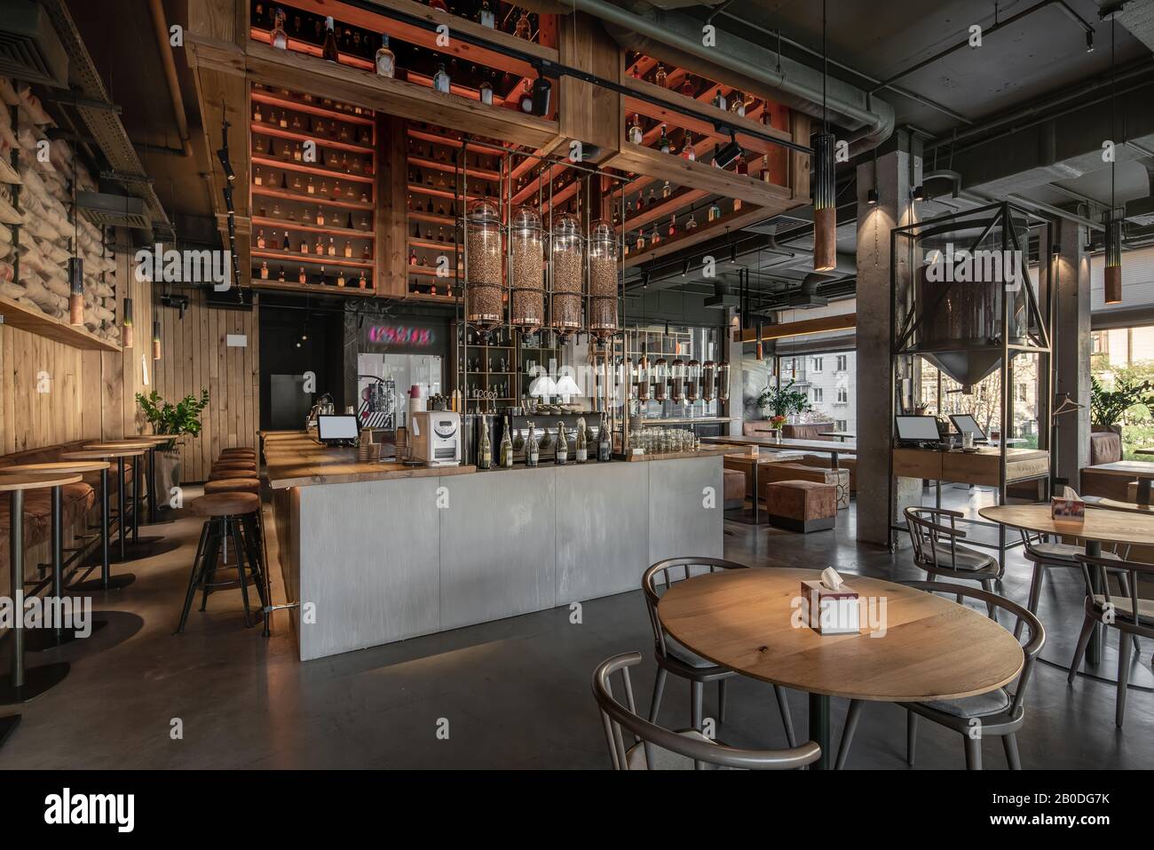 Stylish Coffee House In Loft Style With Big Panoramic Windows And Concrete Columns There Are Wooden Tables With Sofas And Chairs Shelves With Bottle Stock Photo Alamy