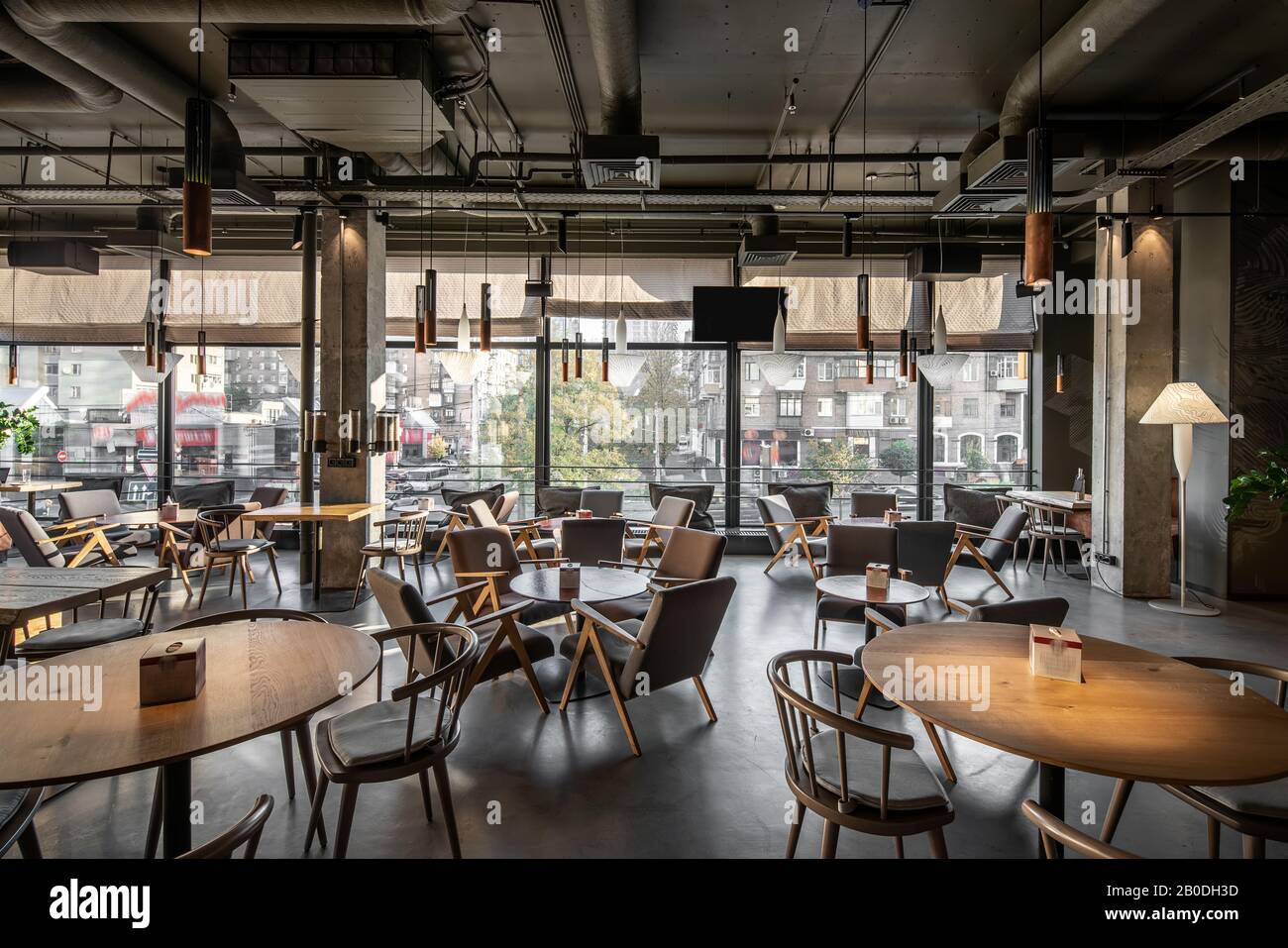 Nice Coffee House In A Loft Style With Big Panoramic Windows And Concrete Columns There Are Round Wooden Tables With Chairs And Armchairs Glass Coff Stock Photo Alamy