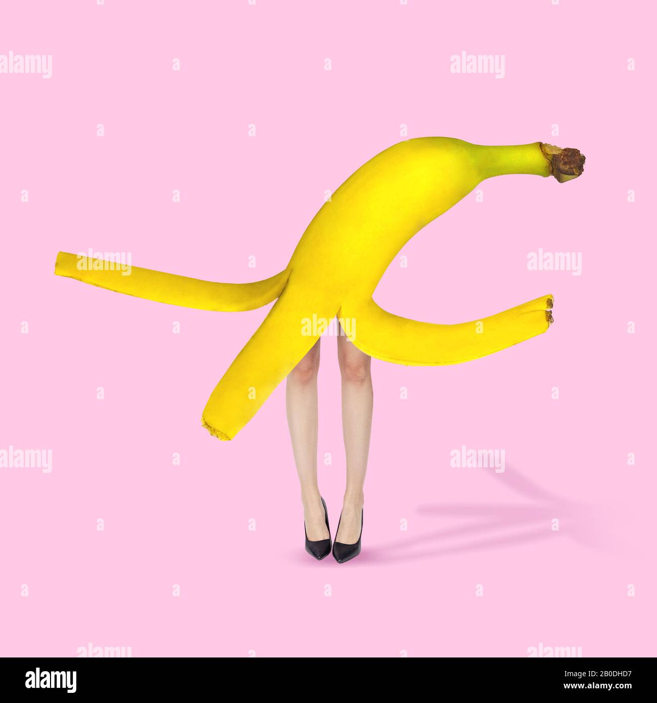 Female body headed by yellow banana on coral background. Copyspace for
