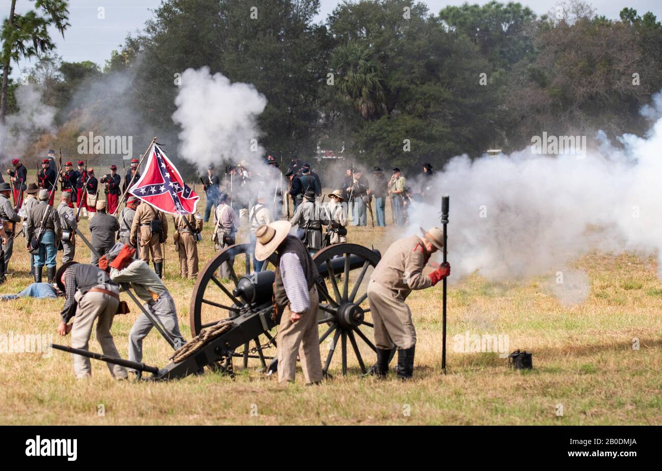 Brooksville, FL - January 19, 2020: Civil War reenactors fire a large canon, with a confederate flag in the background, at an event in Brooksville, FL Stock Photo