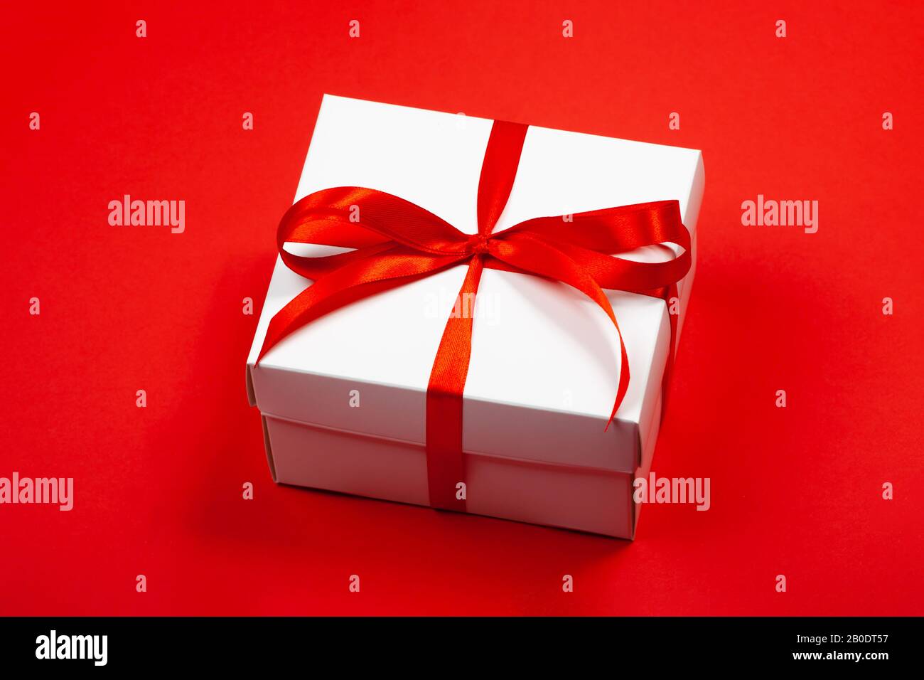 Trendy attractive minimalistic gift on the red background. Women's Day, St. Valentine's Day, Happy Birthday and other holidays concept. Stock Photo