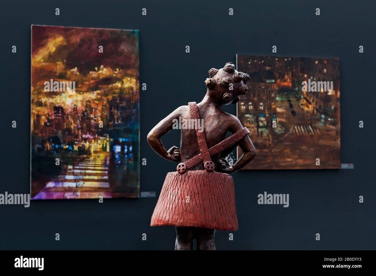 Salzburg / Austria - August 2019: Hangar-7, an exhibition of contemporary paintings and sculptures; a girl's sculpture is regarding paintings. Stock Photo
