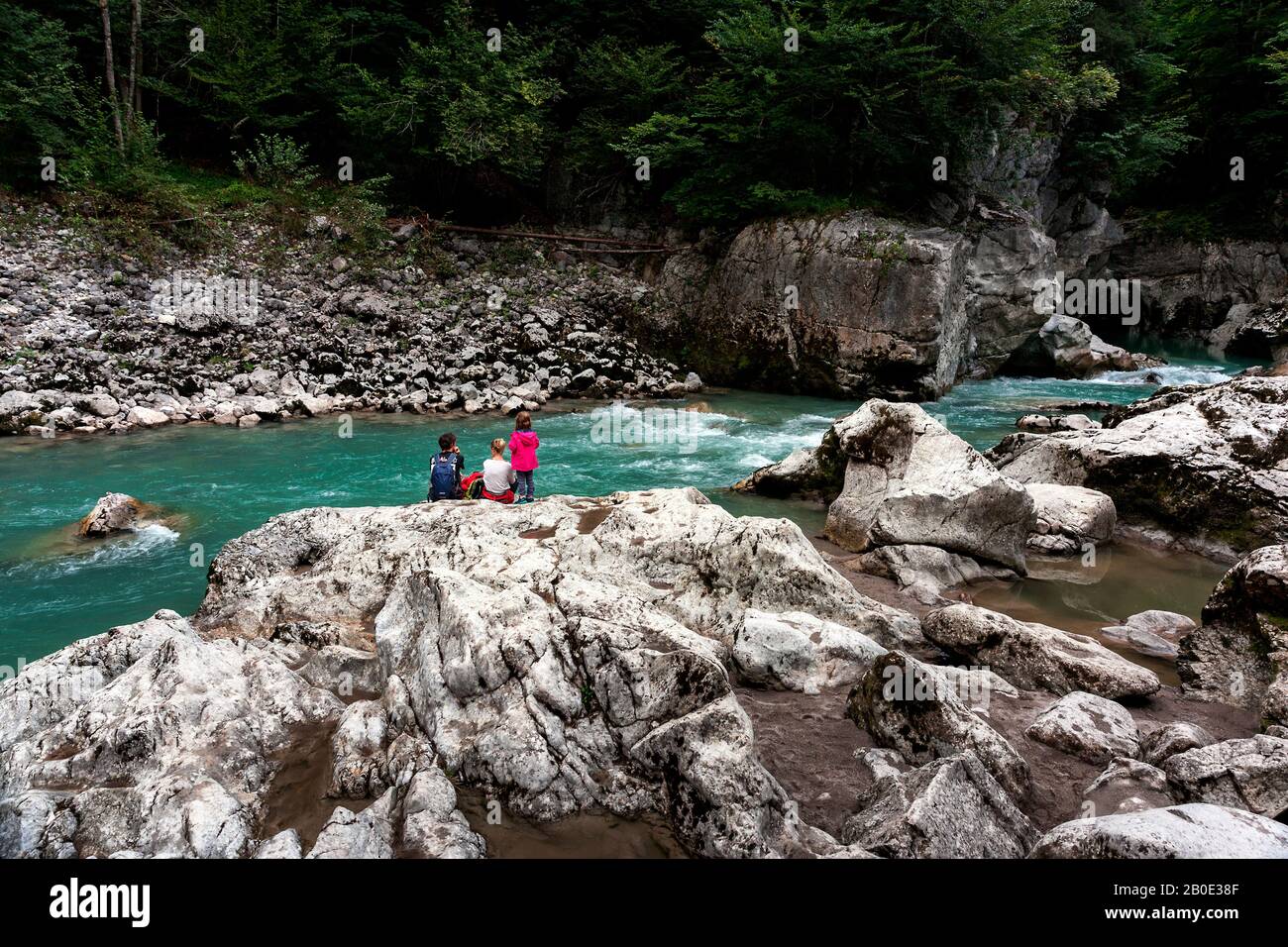 Family resting after trekking on the rocks on the bank of a wild mountain river Stock Photo