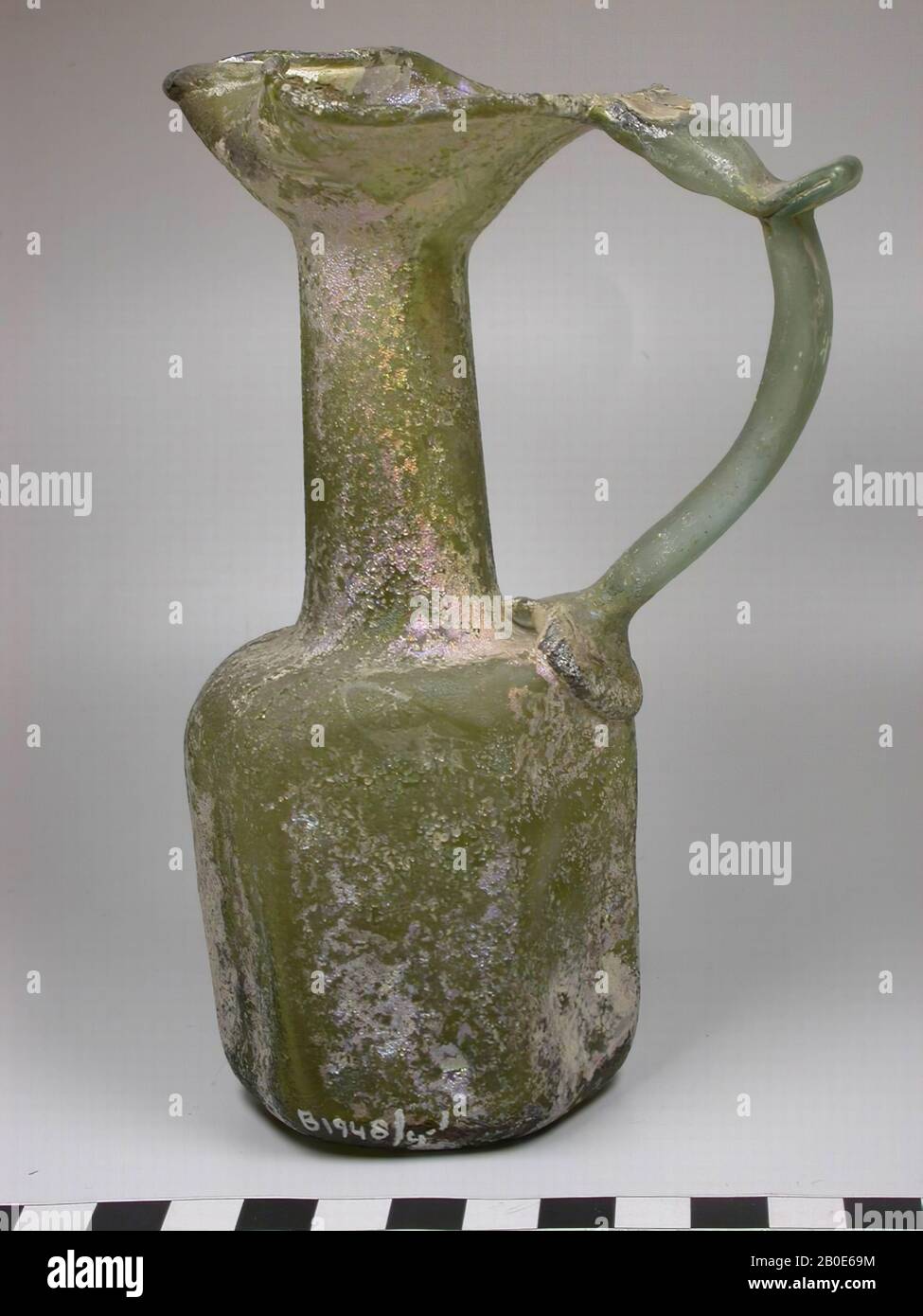 Syrian glass jug with an ear, cylindrical neck, wide mouth with squeezed spout and hexagonal shaped belly with vague relief decoration, tableware, glass, H 15.5 cm, Syria Stock Photo