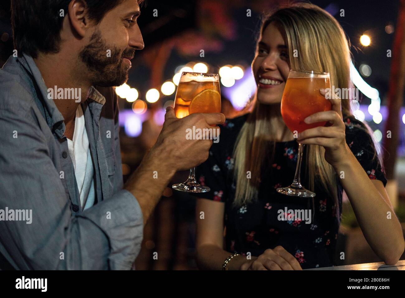 Young couple holding cocktail glasses at outdoor cafe Stock Photo