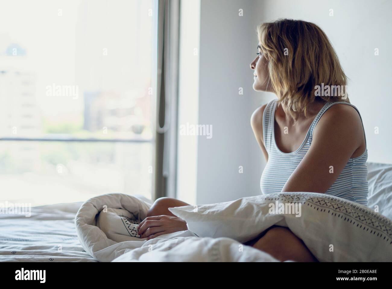 Young woman looking out through window Stock Photo