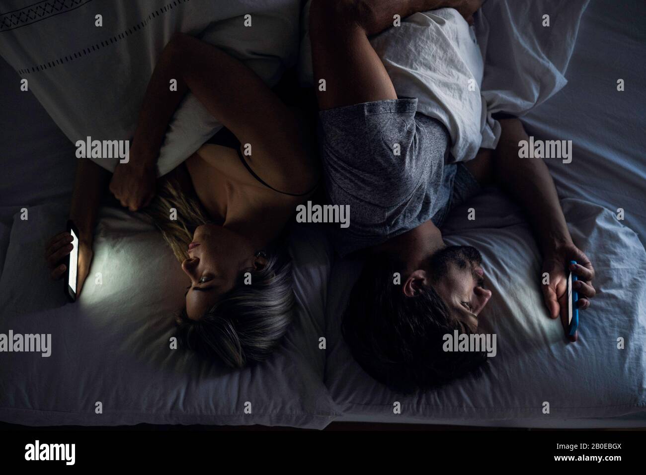 Young couple using smartphones on bed Stock Photo