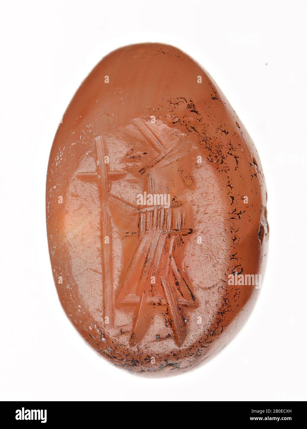 An ellipse-shaped stamp with an image of a standing, male person who stretches a cross-shaped staff forward, seal, stone, carnelian, L 0.8 cm, D 1.2 cm, Iran Stock Photo