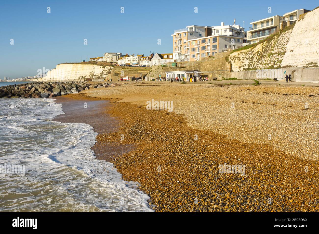 Brighton, England - November 28, 2019: Shingle beach with cafe on promenade at Rottingdean near Brighton in East Sussex, England. With people. Stock Photo