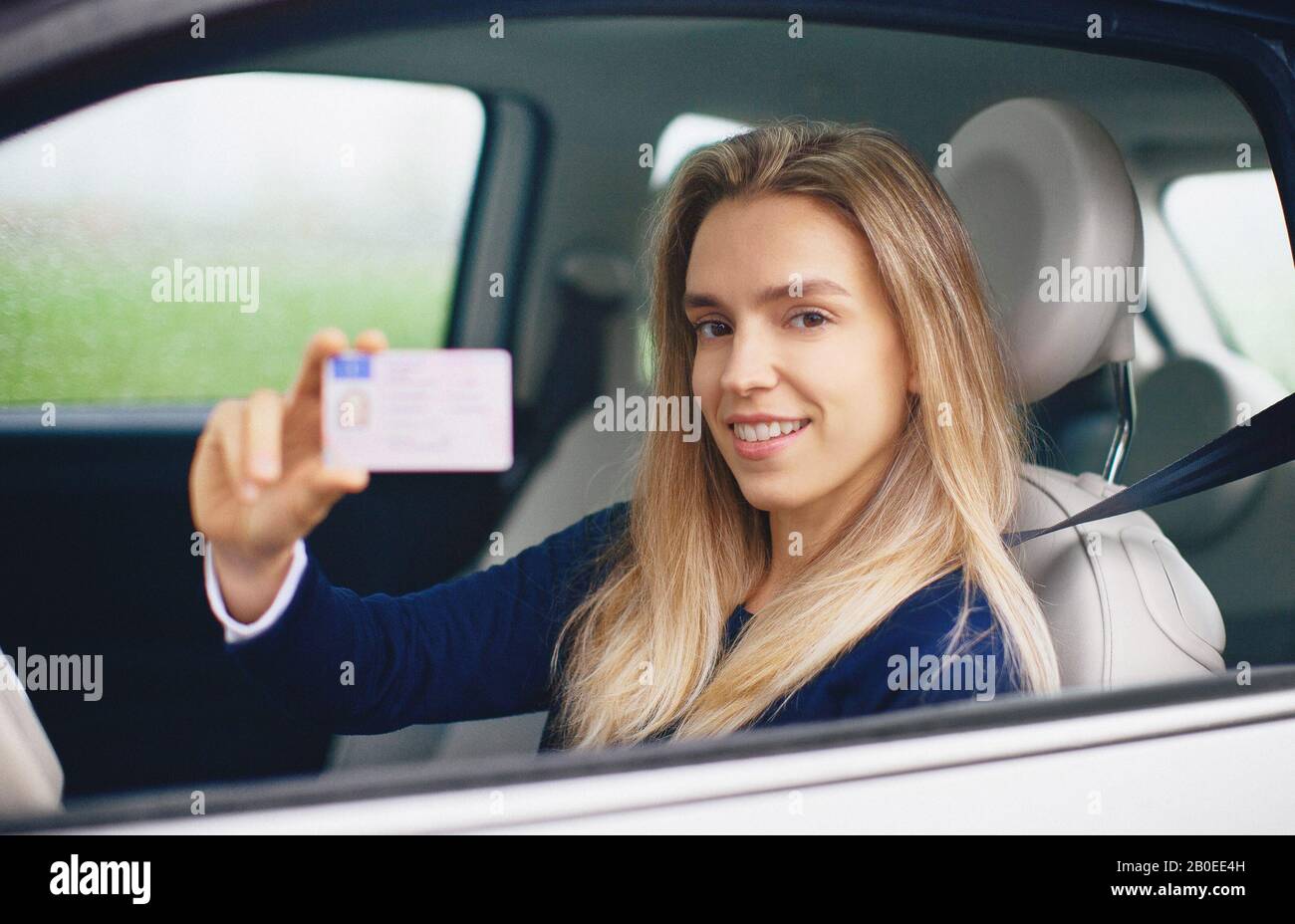 Young blonde woman in her new car smiling. Stock Photo