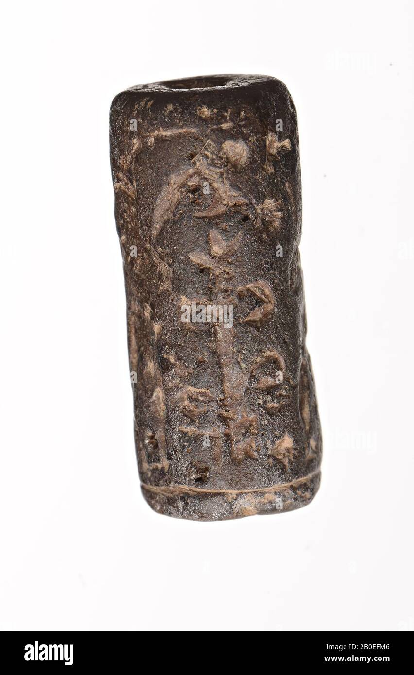A stone cylinder seal with two standing figures with their backs together. A stylized tree is shown between them. Not easily recognizable., Seal, stone, H 2.9 cm, D 1.3 cm, Iran Stock Photo