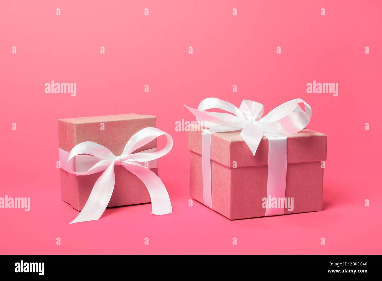 Trendy attractive minimalistic gifts on the coral pink background. Women's Day, St. Valentine's Day, Happy Birthday and other holidays concept. Stock Photo