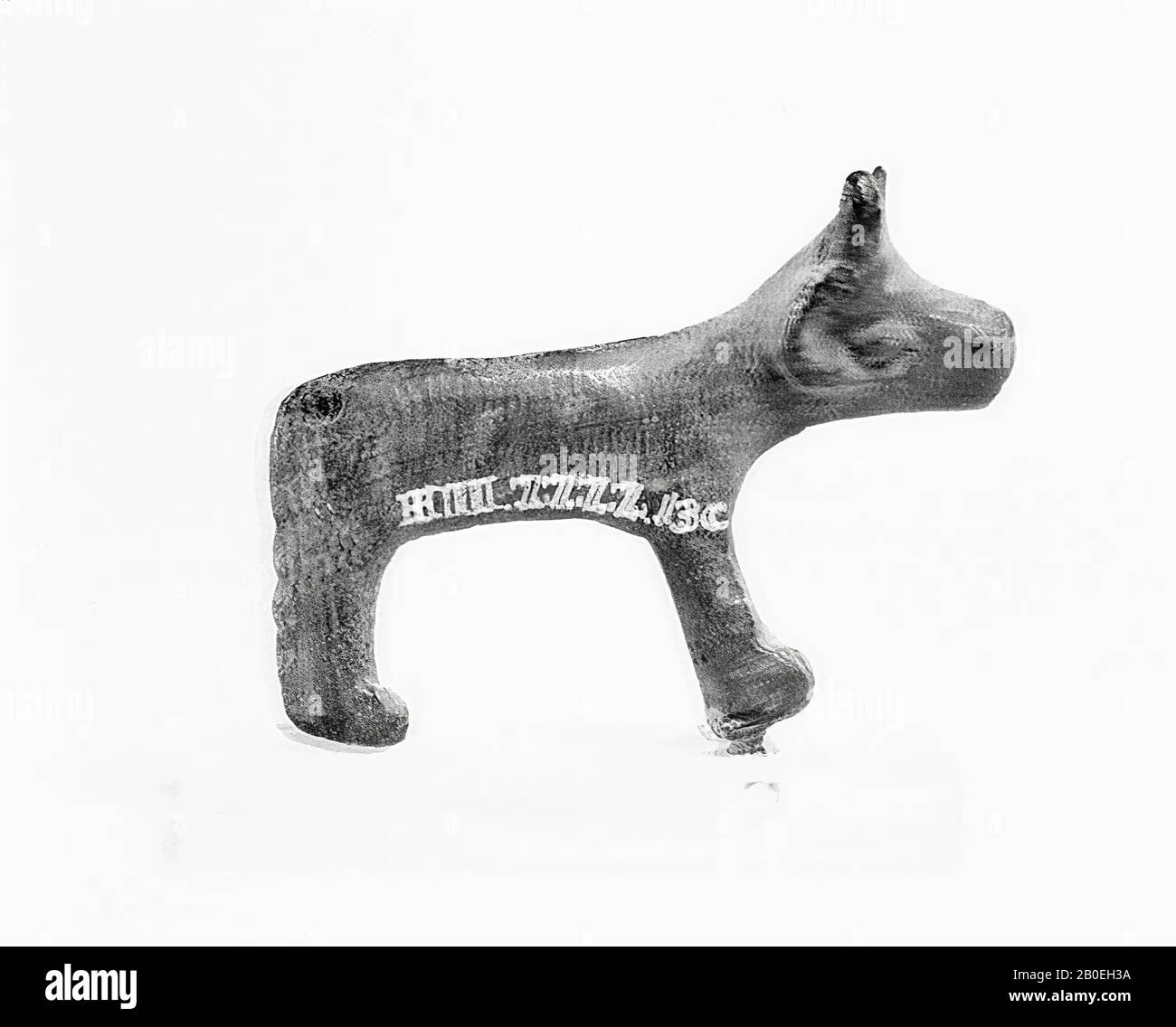 Narrow flat primitive figure. Head from above wide with outstanding horns. Very large eyes, the nostrils are indicated. Both front legs and hind legs form a whole. The long tail hangs straight down., Animal figure, bronze, 5.5 cm, Italy Stock Photo