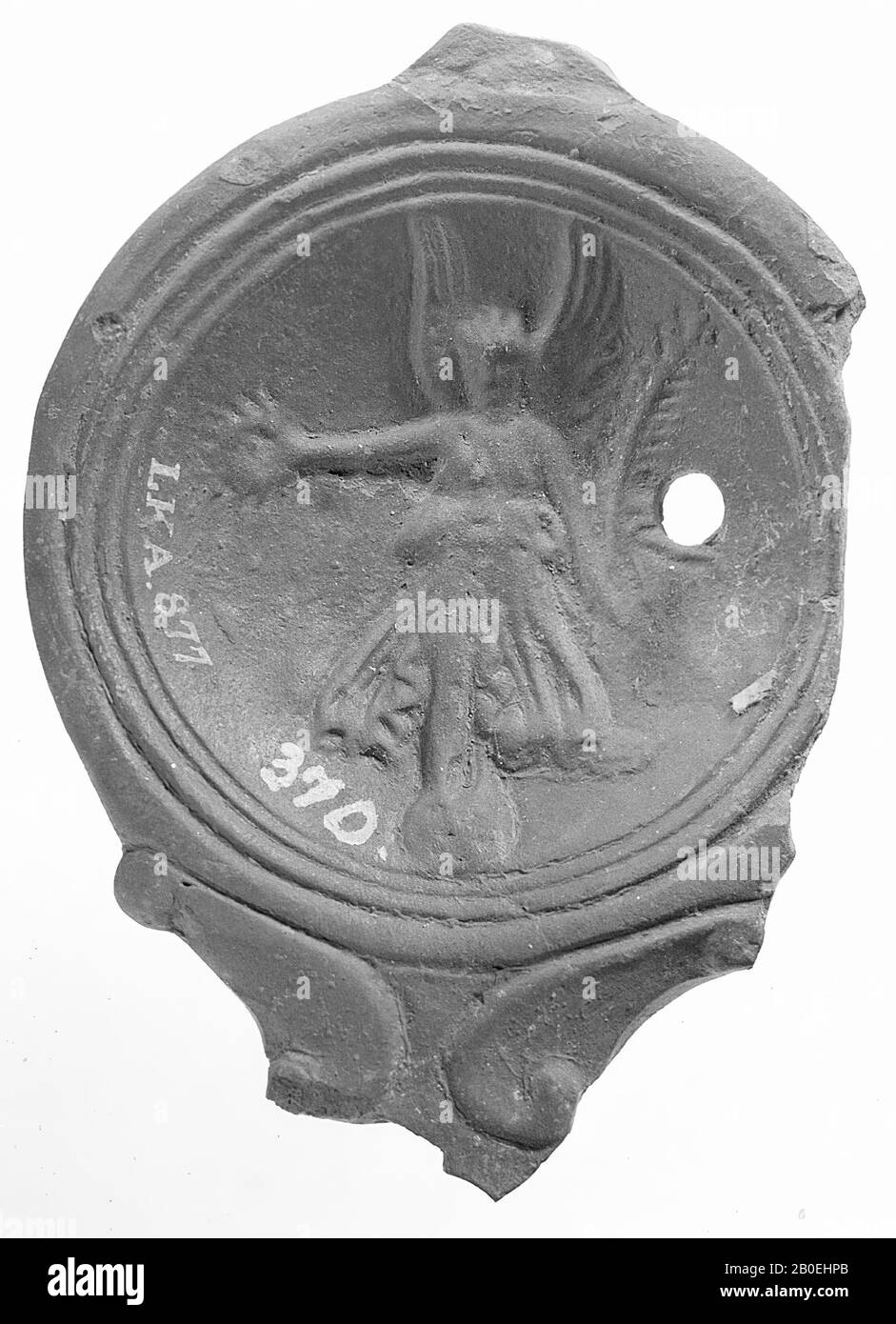 Fragment of a black-nested oil lamp. The hollow mirror is surrounded with concentric circles and decorated with a standing Victoria on a sphere with a wreath and a palm branch. The broad, short spout was decorated with volutes. The small filling hole is to the right of the figure., Oil lamp, earthenware, terracotta, 4 x 9.5 x 7.2 cm, 1st and 2nd century AD. 1-200, Turkey Stock Photo