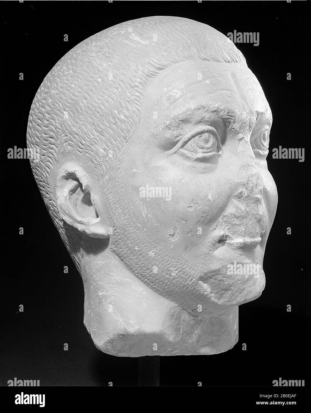Roman portrait head of a fine-grained transparent white marble man with brown-yellow patina. The piece lacks many details, especially in the hair, on eyebrows, nose, upper lip and chin. The head has broken off in the middle of the neck. Very short shaved hair is shown schematically with thin kerf lines. This also applies to the beard and the mustache. There are lines in the forehead, which are not sculpted out of plastic, but rather engraved. As a portrait, the East Roman piece seems to have little individuality., Head, man's head, Roman portrait head, marble, height 28 cm, width 18 cm, depth Stock Photo