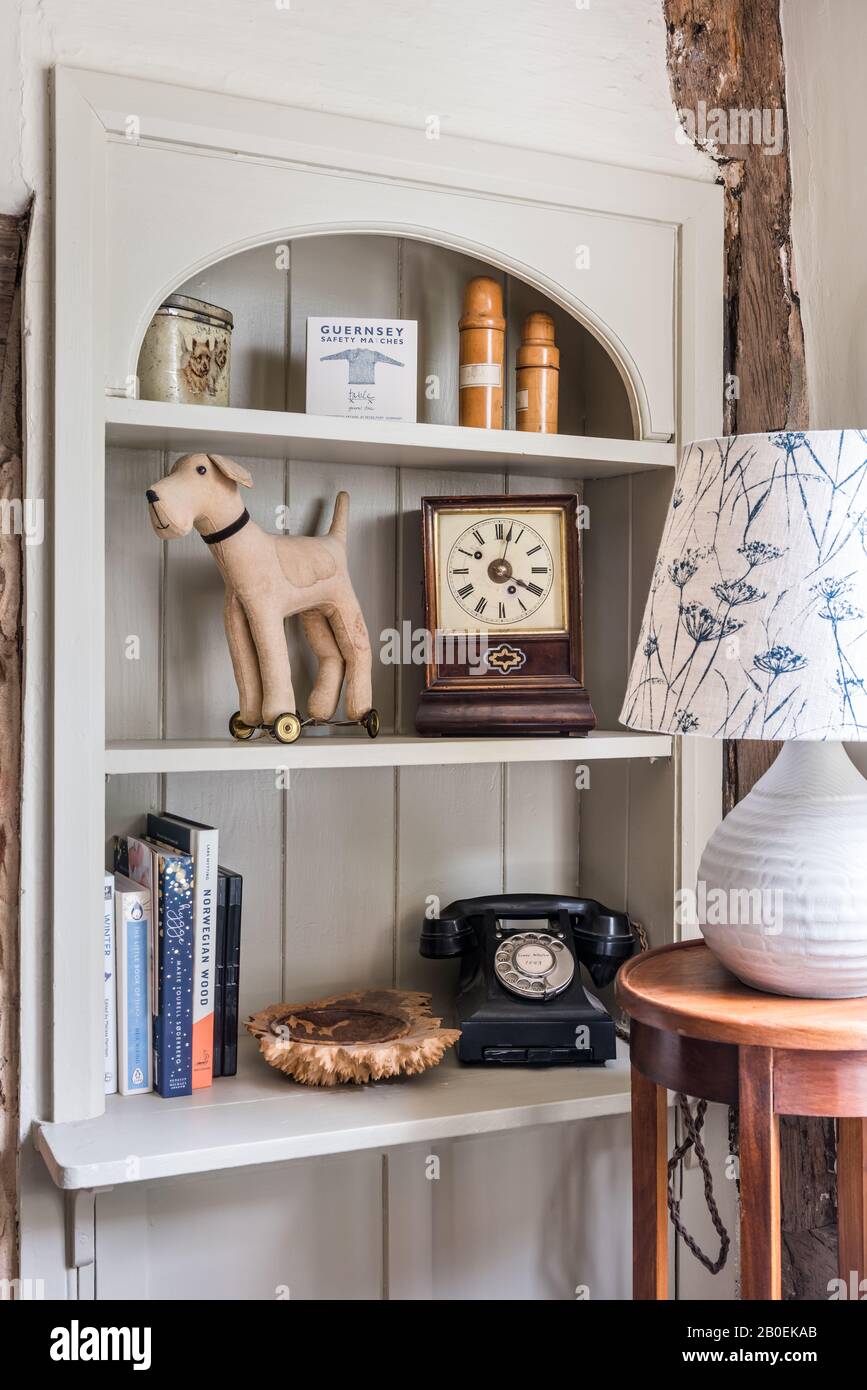 Tongue-and-groove shelving with antique clock. vintage phone and dog on wheels. Stock Photo