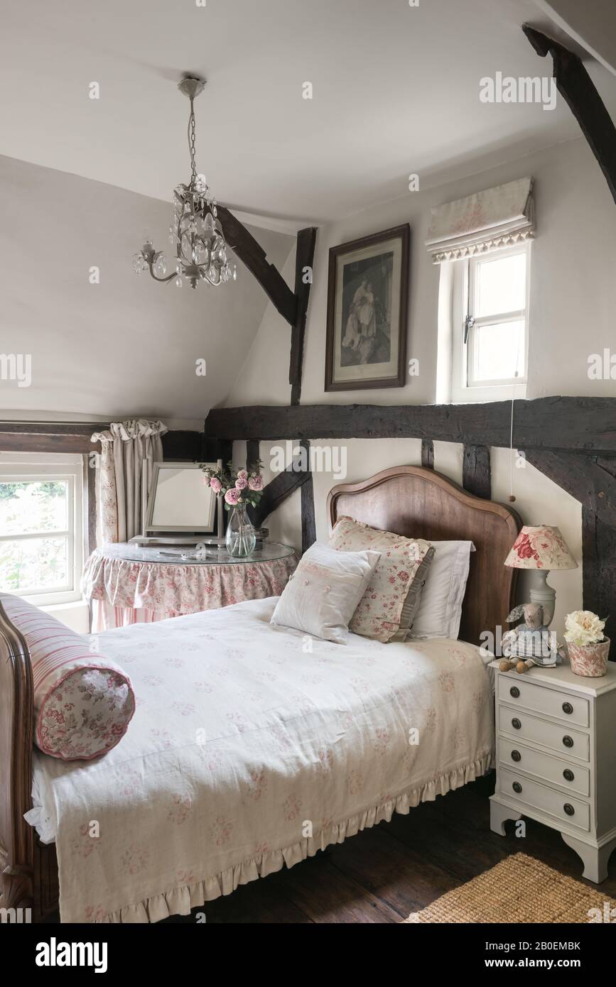 Vintage fabrics in room with antique French bed and original wooden floorboards and beams Stock Photo