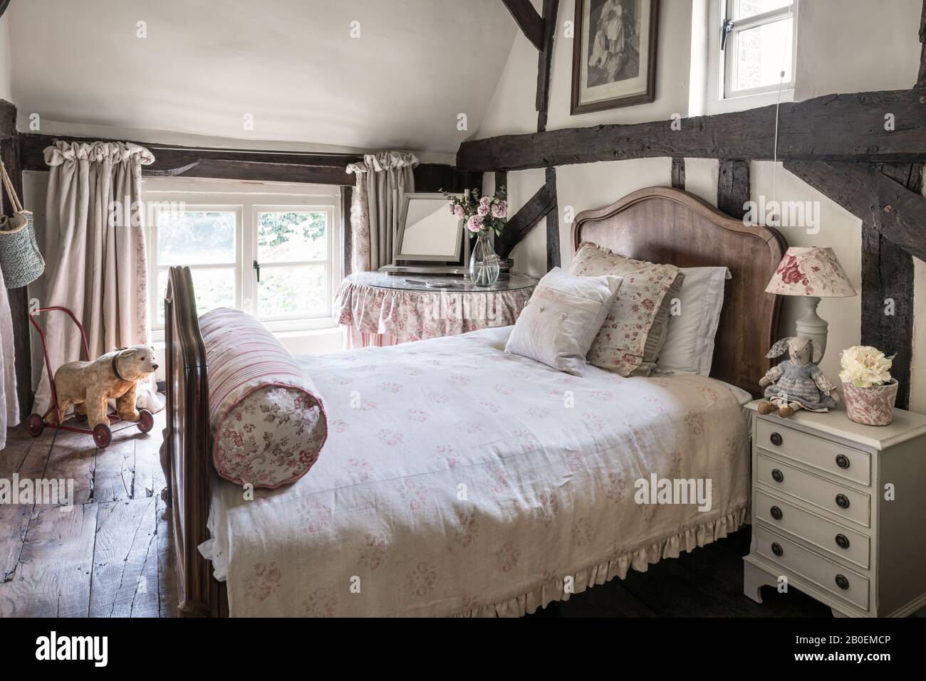 Vintage fabrics in room with antique French bed and original wooden floorboards and beams Stock Photo