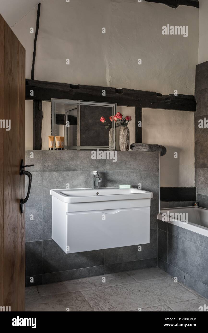 Uneven plastered walls contrasted by clean lines of contemporary basin unit. Stock Photo
