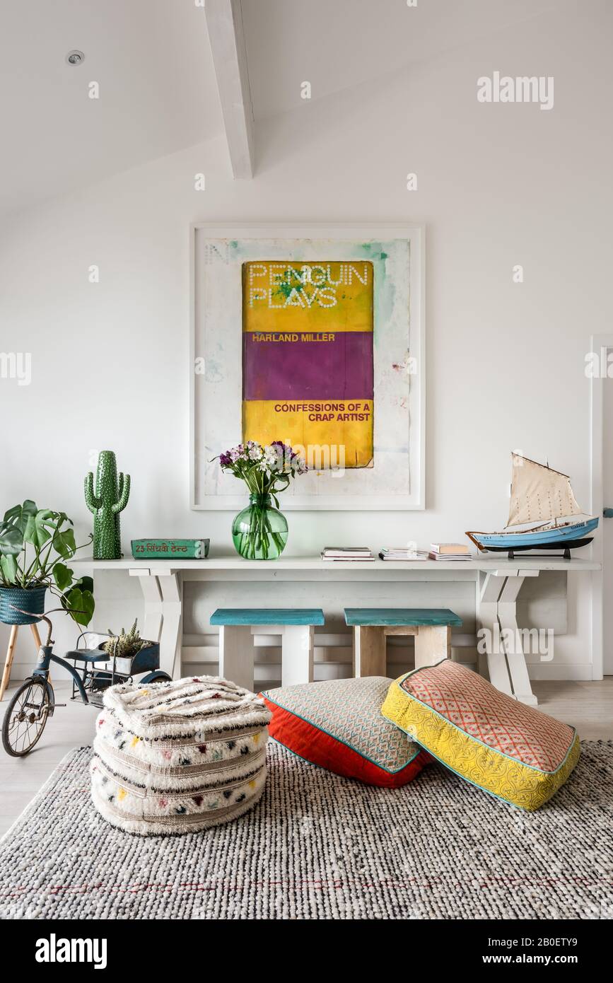 Framed art above console table with floor cushions Stock Photo Alamy