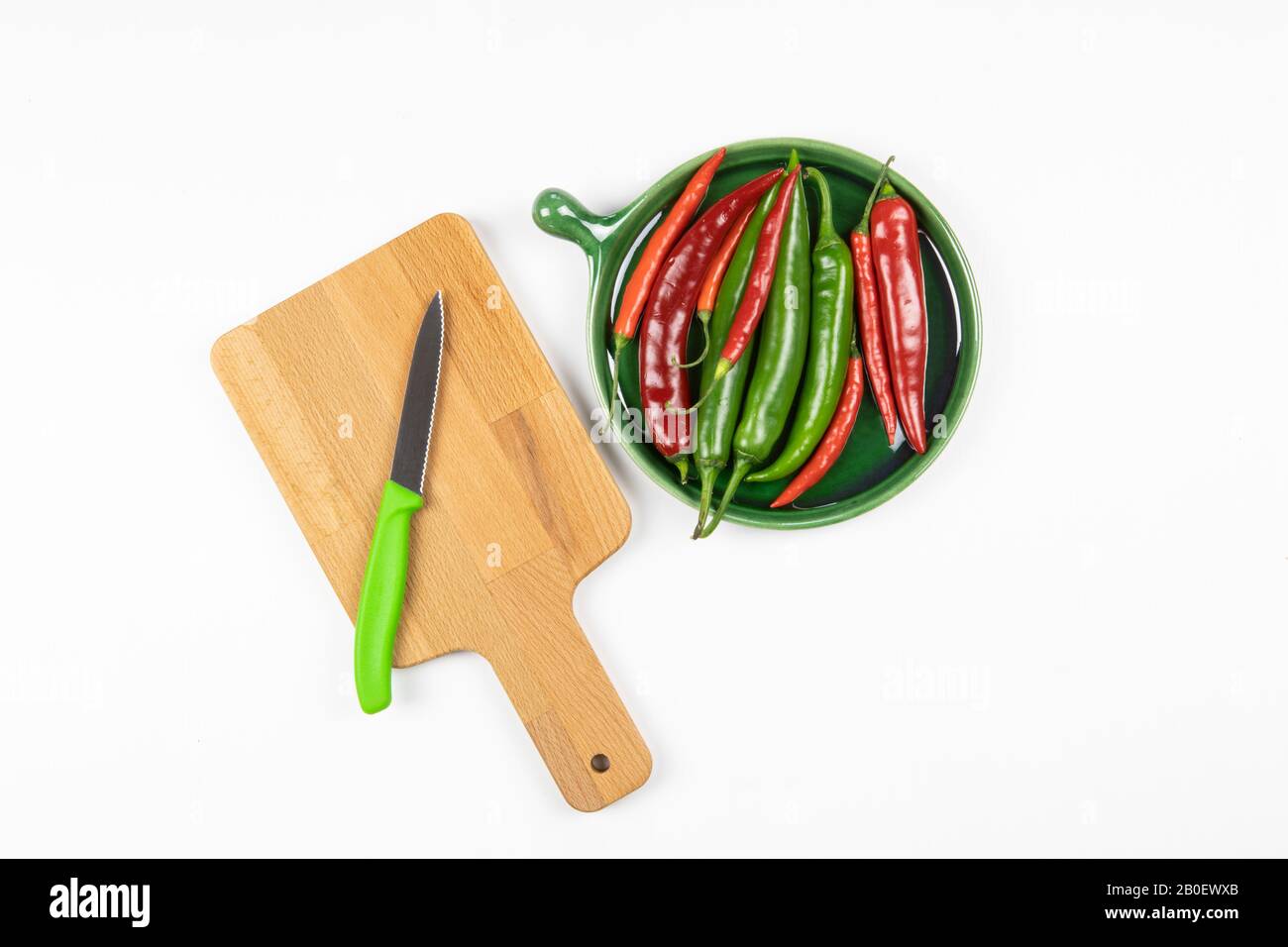 Green and red hot chilli peppers on green plate, chopping board with ...