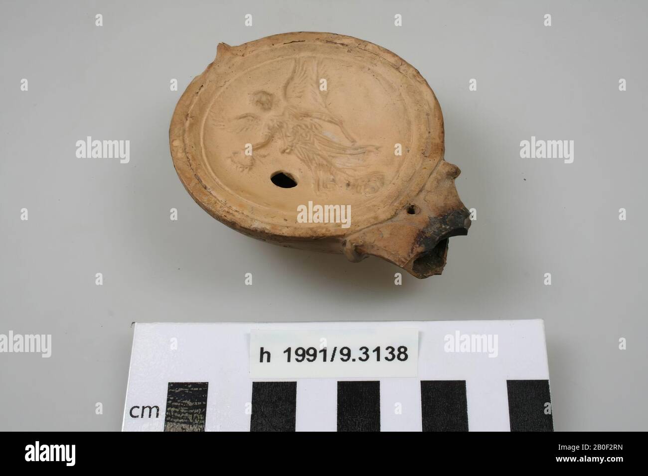 Pottery oil lamp, decorated with an image of Victoria, with spout, filler hole, fire hole and air hole. Traces of fire on the spout, partly missing, the ear is missing., Oil lamp, earthenware, 8,9 x 7 x 2,6 cm, roman, Netherlands, South Holland, Katwijk, Valkenburg Stock Photo