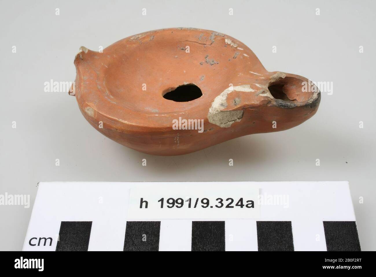 Oil lamp of painted earthenware, with spout, filling hole and fire hole. The ear is missing, gap in the mirror at the filling hole, surface damage at the top, at the spout., Oil lamp, pottery, 9.5 x 6.8 x 2.9 cm, Roman, Netherlands, South Holland, Katwijk, Valkenburg Stock Photo