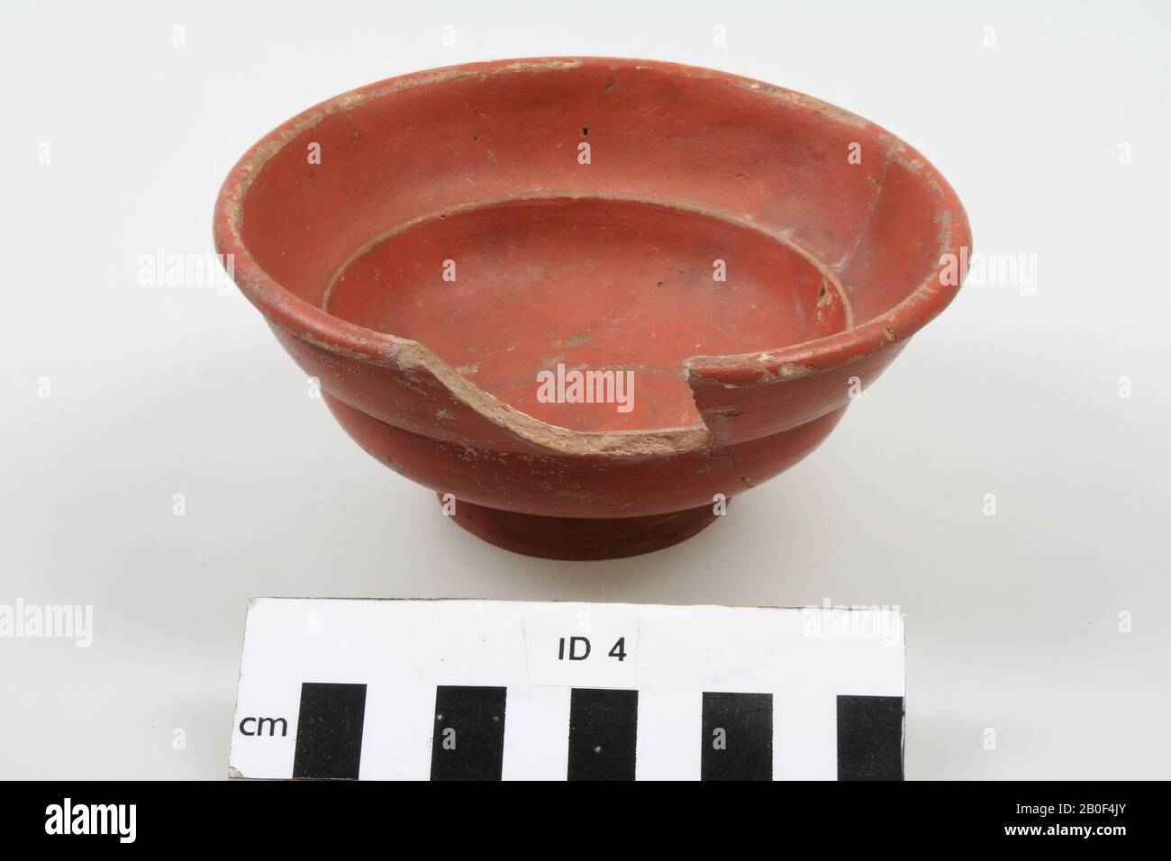 Terra sigillata bowl, Dr. 27, nicely even and rather dark red, everywhere inside and outside. Broken, one piece fitted appropriately, one bite at the top edge. Scraps of red here and there. As a whole, however, the container is still good. In the middle of our piece, the not-too-readable stamp AVSTERINM, low relief letters in shallowly pressed rectangular stamp field. Not well-drawn groove circle, with overlapping of beginning and end around stamp field., Bowl, earthenware, terra sigillata, h: 6 cm, diam: 12,6 cm, roman End 1st or early 2nd century after Chr., Netherlands, Gelderland Stock Photo