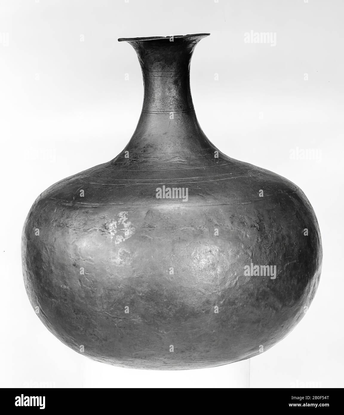 Can from bronze tin on almost flat bottom. Spherical belly, narrow neck narrowing to the middle and curved edge. Hardly patinated, red, copper-colored. Turnings on neck and shoulder, tableware, jug, metal, bronze, height: 17,5 cm, roman 1-200, Netherlands, North Brabant, Grave, Grave, Meuse Stock Photo