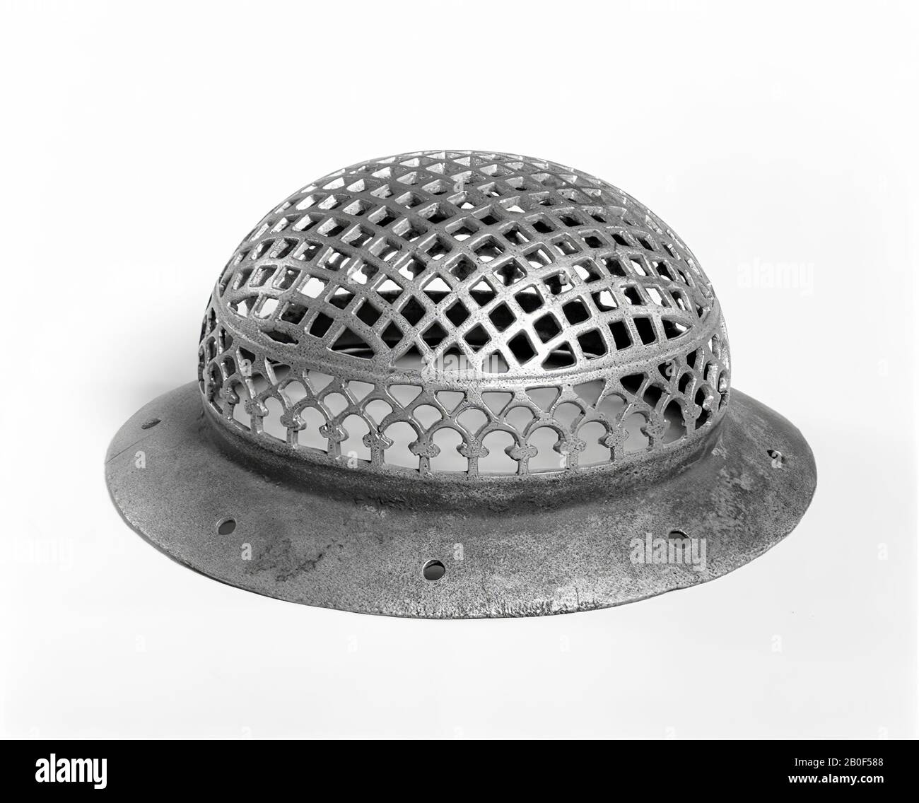 Bronze eye protector of a horse. On a conical bottle rim with 8 perforations, a hemisphere completely cut out into grilles. From below, successively: arcs on small columns, at the top of which to both sides a bulge, triangles. Then a relatively wide, circular ring with a central quarry. Above it, filling the entire convex part, a grille, created by looking at windows. Our ex. was possible part of a leather horse harness., cap, horse eye protection, metal, bronze, height: 6,5 cm, roman 1-300 AD, Netherlands, North Brabant, Oss, Lith, Maas Stock Photo