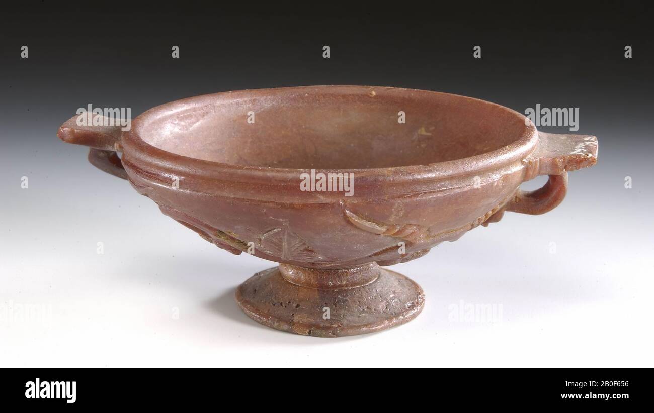 Barn stones miniature kylix. 8 cm wide. With separate foot and wide angular ears. The outside is carved in relief with a branch with leaves and fruits., Kylix, organic, amber, height: 3.5 cm, roman 100-200 AD, Netherlands, Limburg, Heerlen, Heerlen, coffin 4 Stock Photo