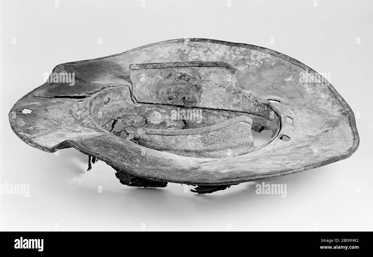 Section of a helmet, wsch. of a champion, with a very broad edge. The upper part that covered the head is largely lost. On the inside there is still a circumferential plate attached to the circumference on both sides, which has been bent at the lower edge, perhaps that edge or band also ran through at the rear, but at the front only to the point where the wide edge of the skin begins and where the vision is confirmed. The edge of the helmet consists of a double plate, rounded and reinforced on the outside with a bent band. All around, there are sitting, walking and jumping animals, lions Stock Photo