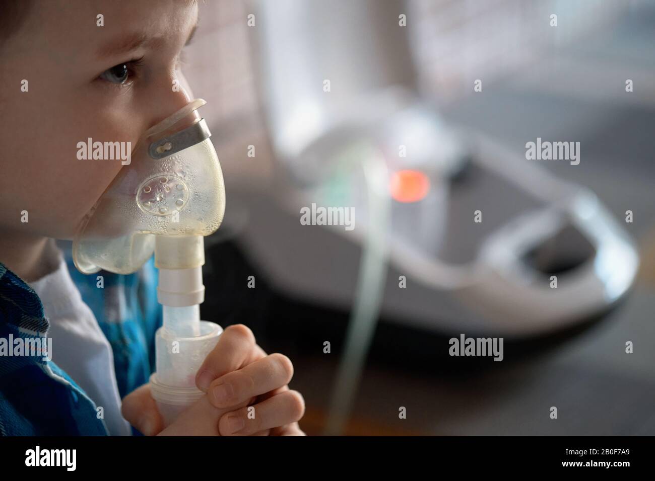 Child makes inhalation at home with nebulizer on out of focus background. Example of combating respiratory diseases such as tracheitis bronchitis pneu Stock Photo