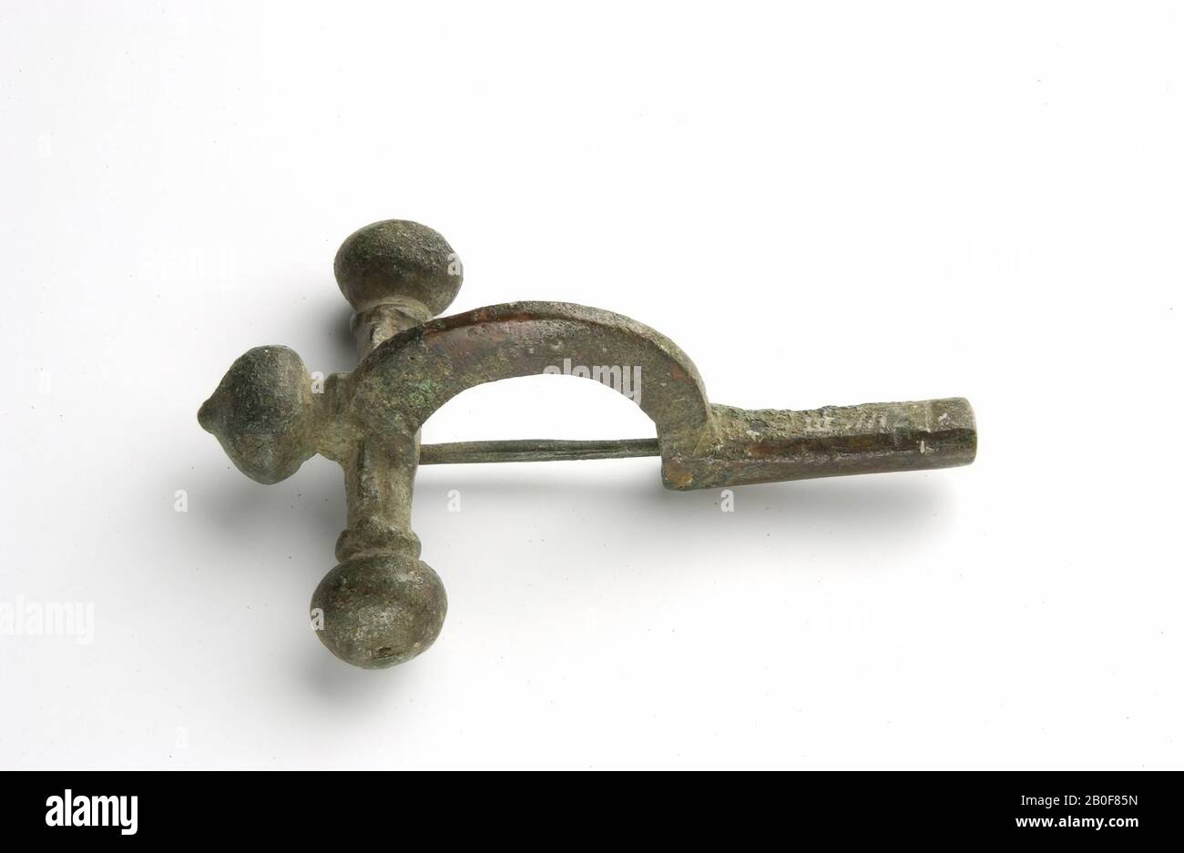 Bronze crossbow fibula, the bow on top with a bud, including a crossbar, whose ends end in round buds, the lower end of the arch ending in a hollow pin, in which the needle closes in an upright slot, fibula, crossbow fibula, metal, bronze, 7,4 x 4,9 x 2,9 cm, roman 290-325 AD, Netherlands, Gelderland, Nijmegen, Nijmegen, Waal Stock Photo
