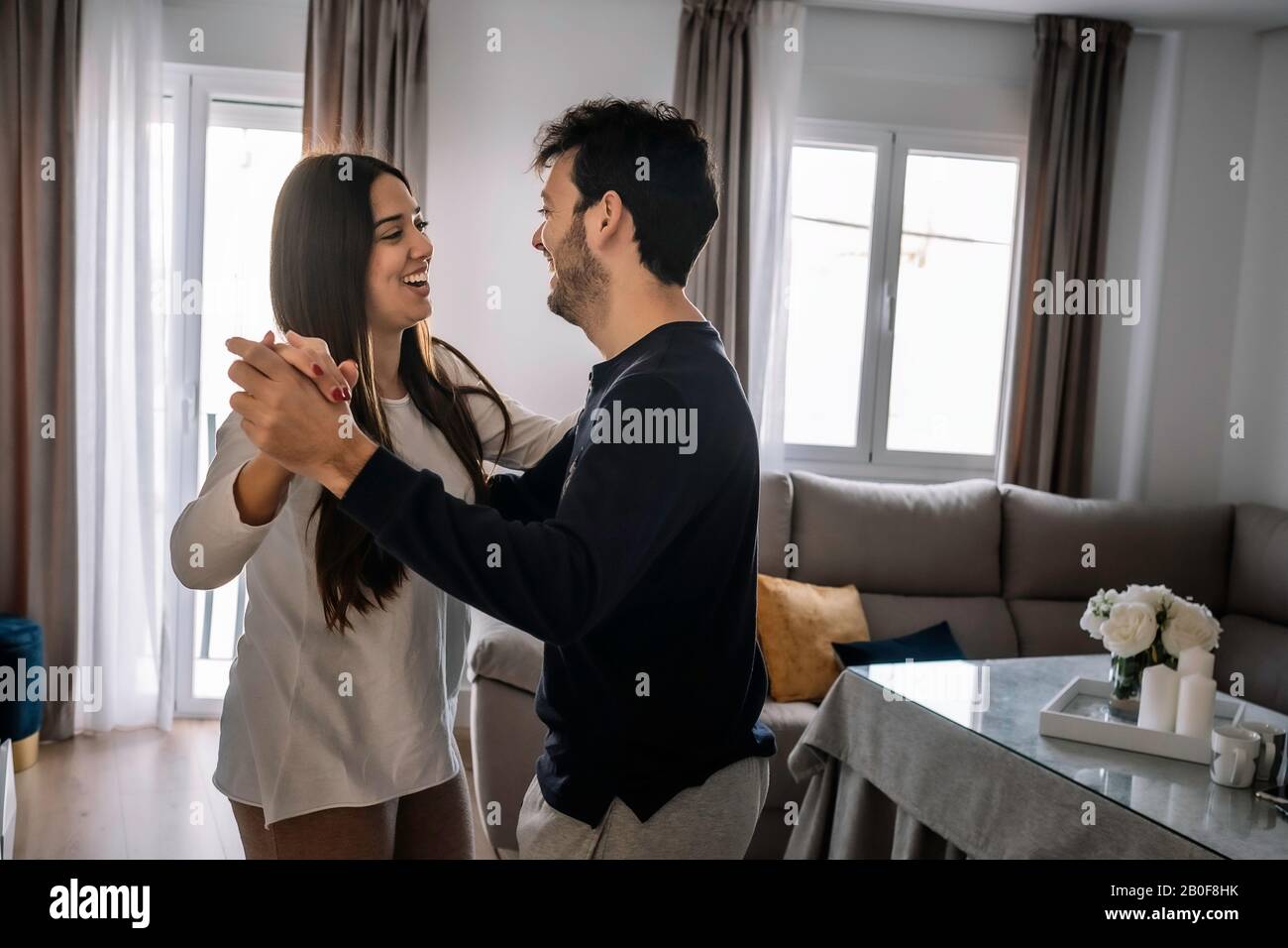 young couple smiling, dancing inside their house Stock Photo