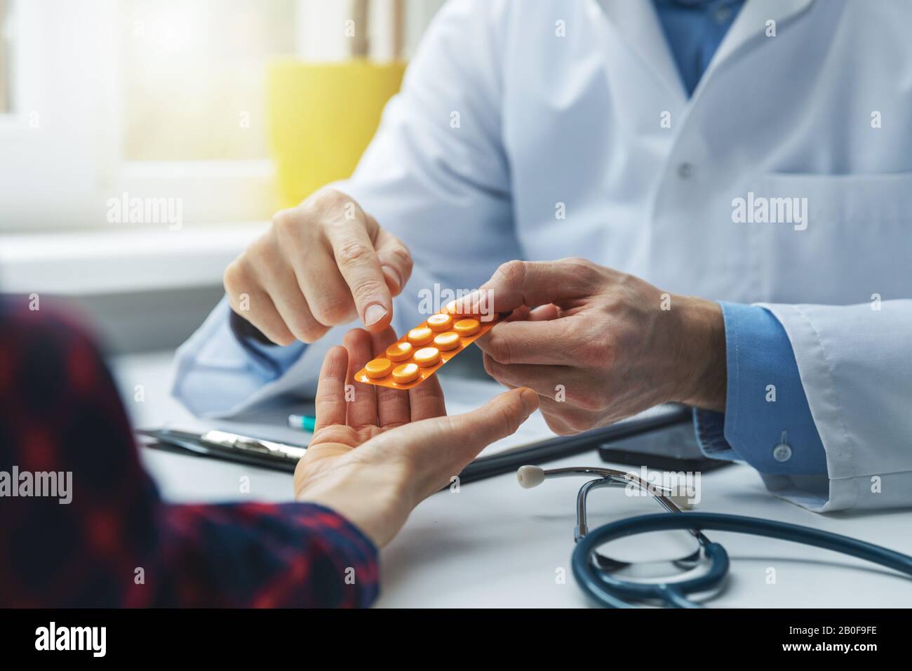 physician consulting female patient about pills. doctor prescribing medicine sitting at the desk in the clinic office Stock Photo