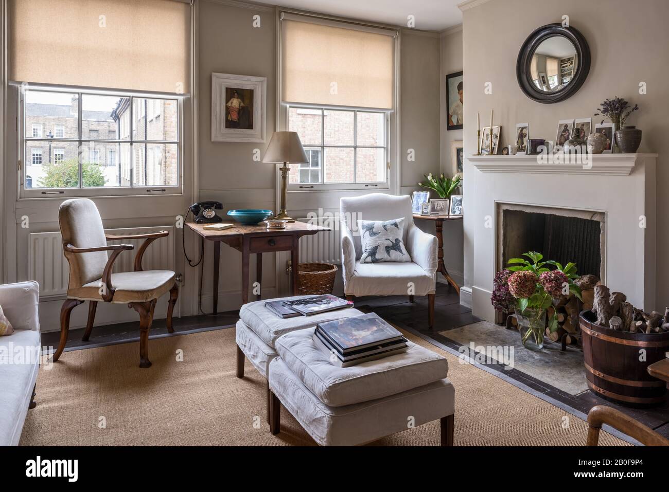 Upholstered armchair by Stephen Pardy with footstools for extra seating at windows in Georgian townhouse. Stock Photo