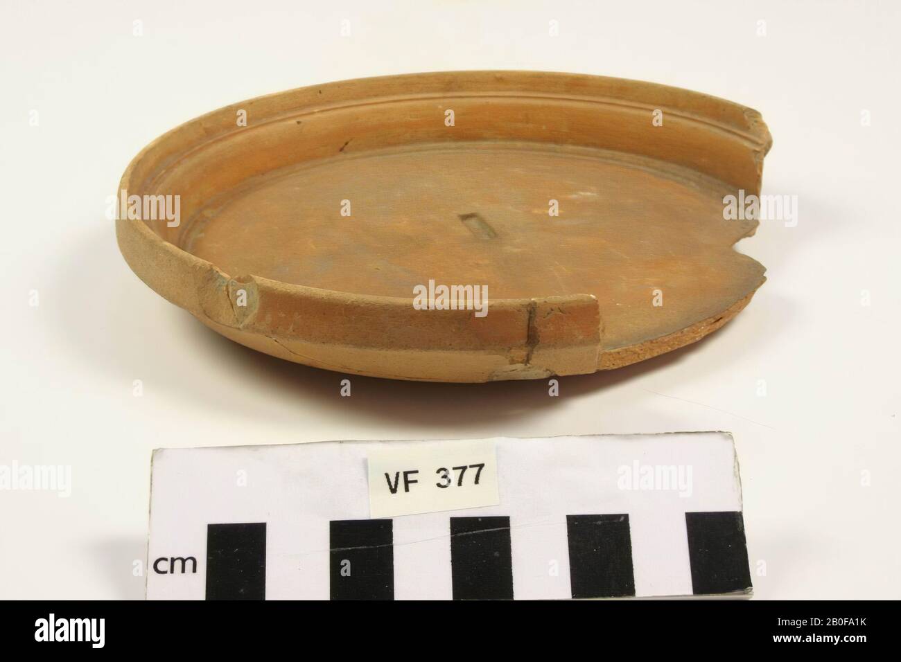 Smooth wall plate of so-called Belgian ware with an unreadable stamp in the bottom. A part of the edge and the bottom is missing, in addition some old gluing and surface damage., Plate, pottery, h: 2,6 cm, diam: 15,5 cm, roman, Netherlands, Utrecht, Bunnik, Fighting Stock Photo