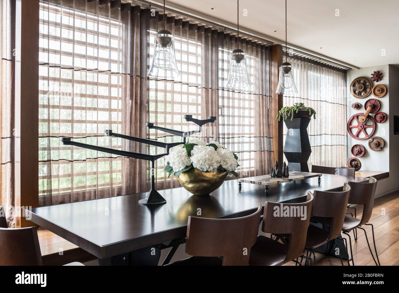 Glass pendant lights above dining table from Arxe with hydrangea in copper vase Stock Photo